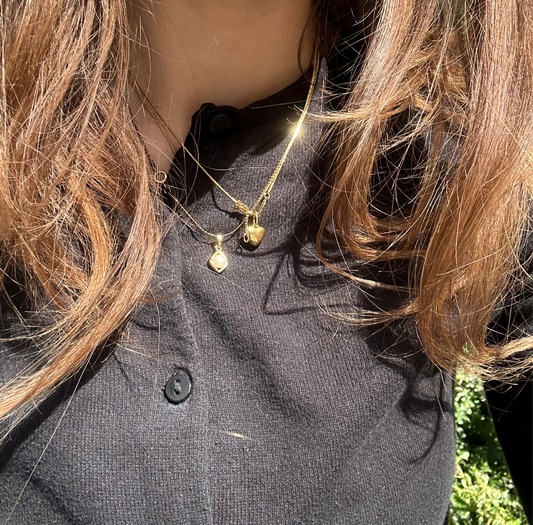 Kani Halskette und Herz aus Gold Halskette in Gold getragen im Sonnenschein auf Mädchen