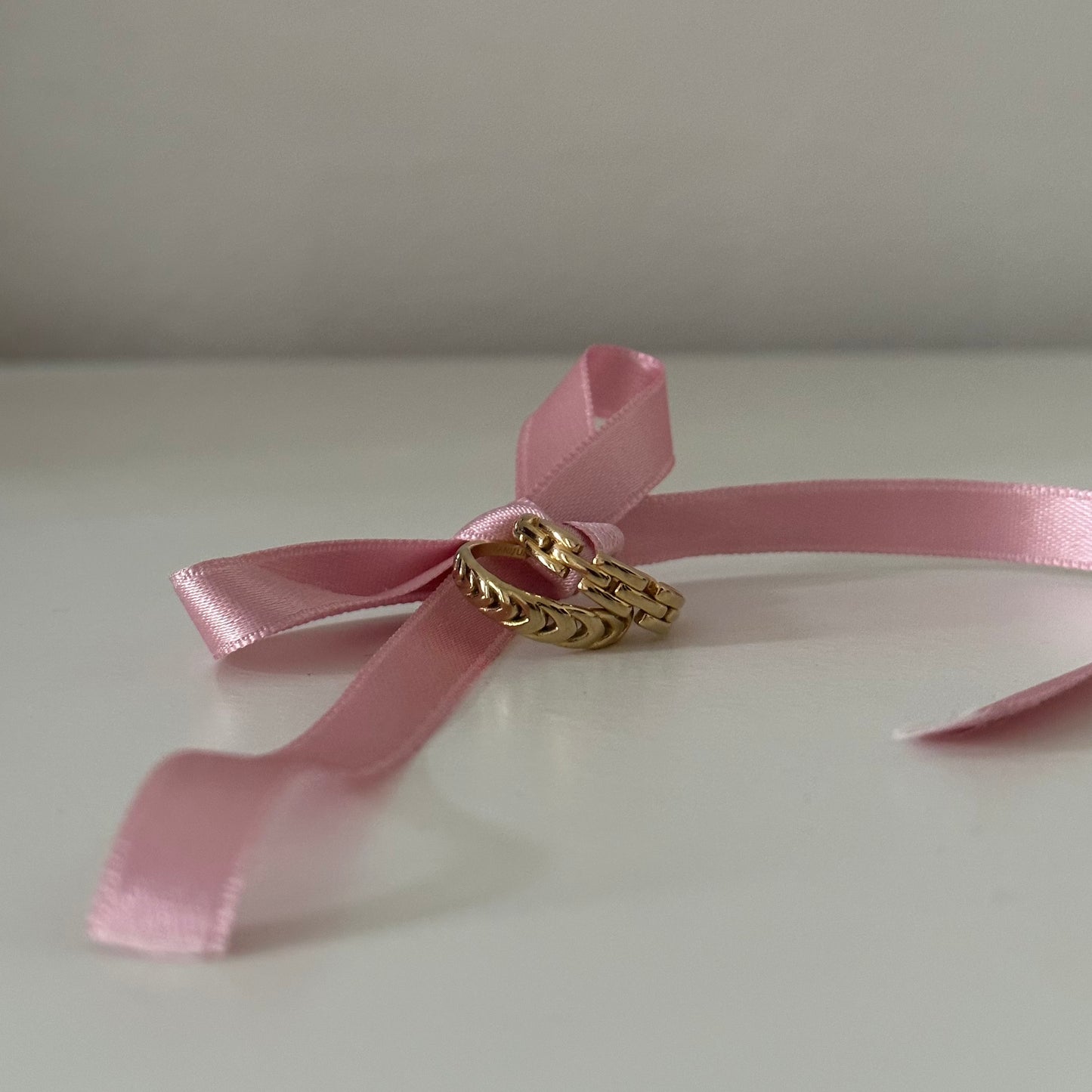 zwei goldene Ringe an einer Rosa Schleife