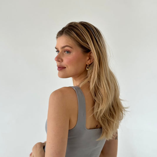 Ricky Ohrringe, getragen von einem blonden Mädchen vor einer weißen Wand