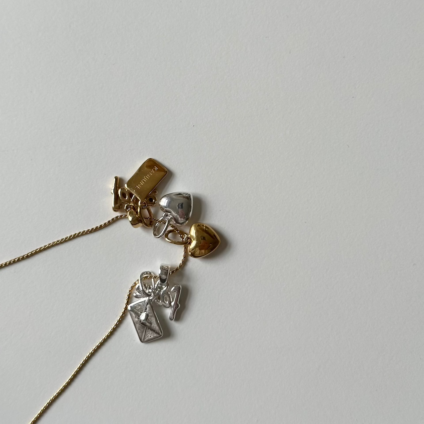 necklace with lots of charms in silver and gold on white table