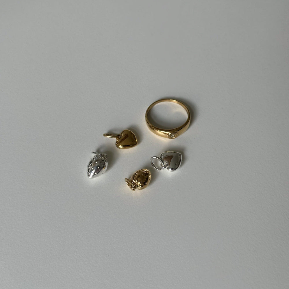 gig ring and heart of gold charm and strawberry charm on white background