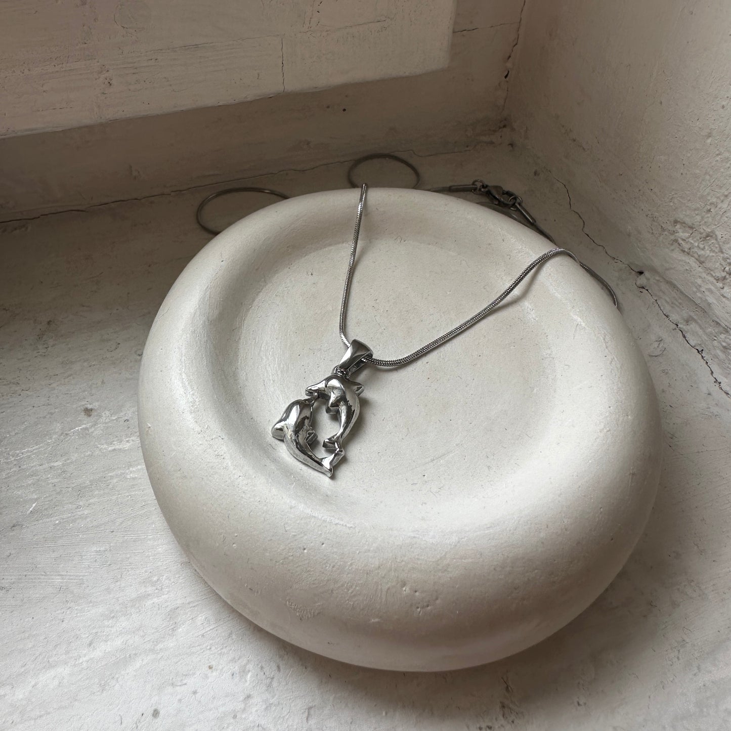 Dancing Dolphin Delfin Kette in silber auf weißer Keramikschale