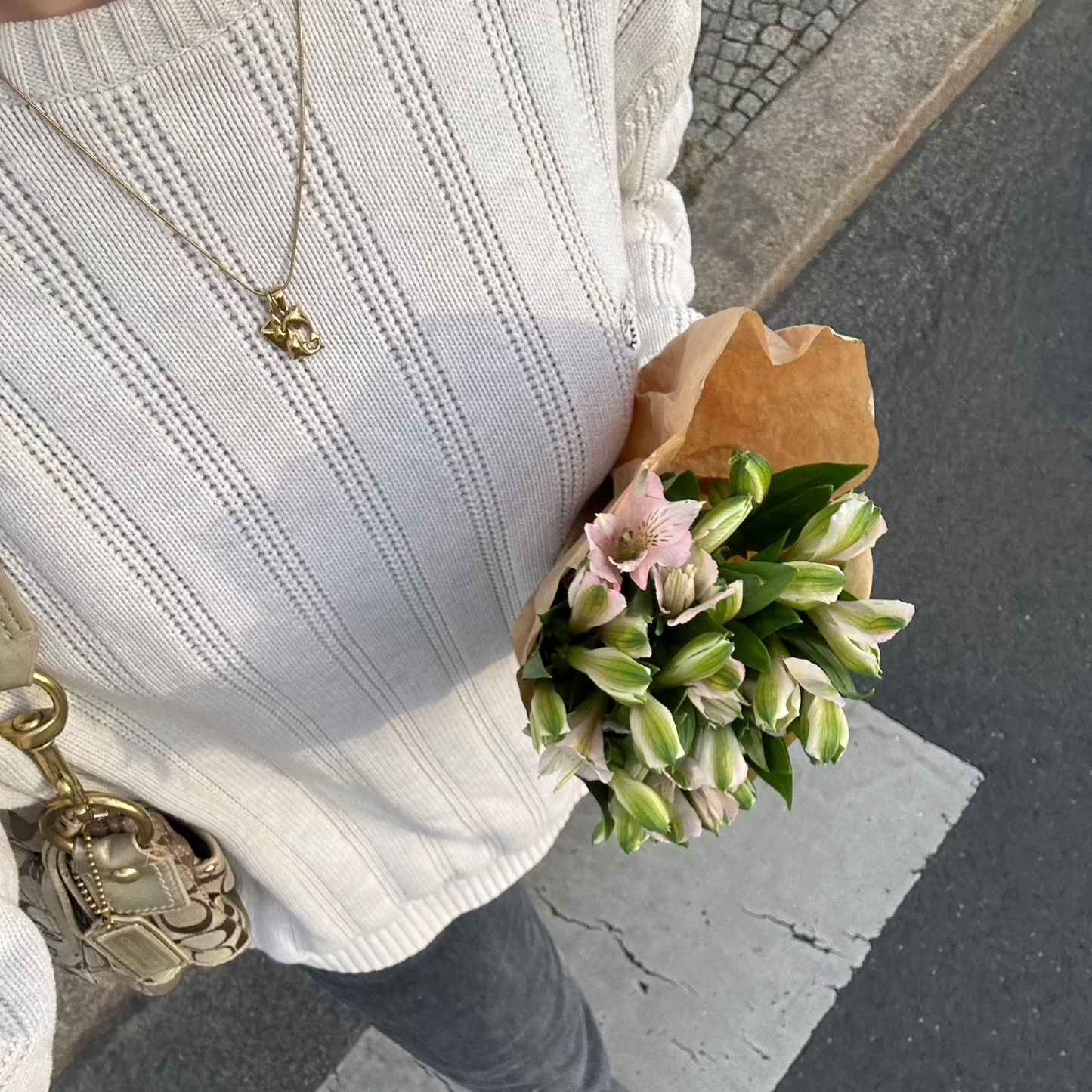 gold necklace worn while holding flowers looking down on the streets