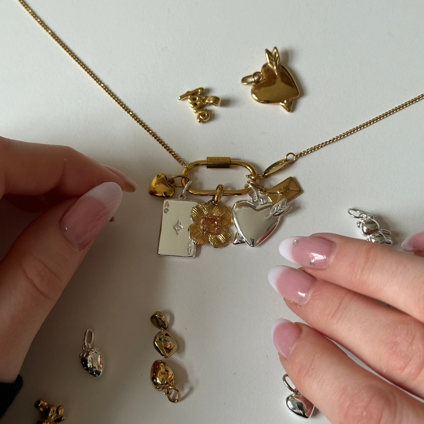 mix and match necklace on white background and hands on the sides which just hold the necklace
