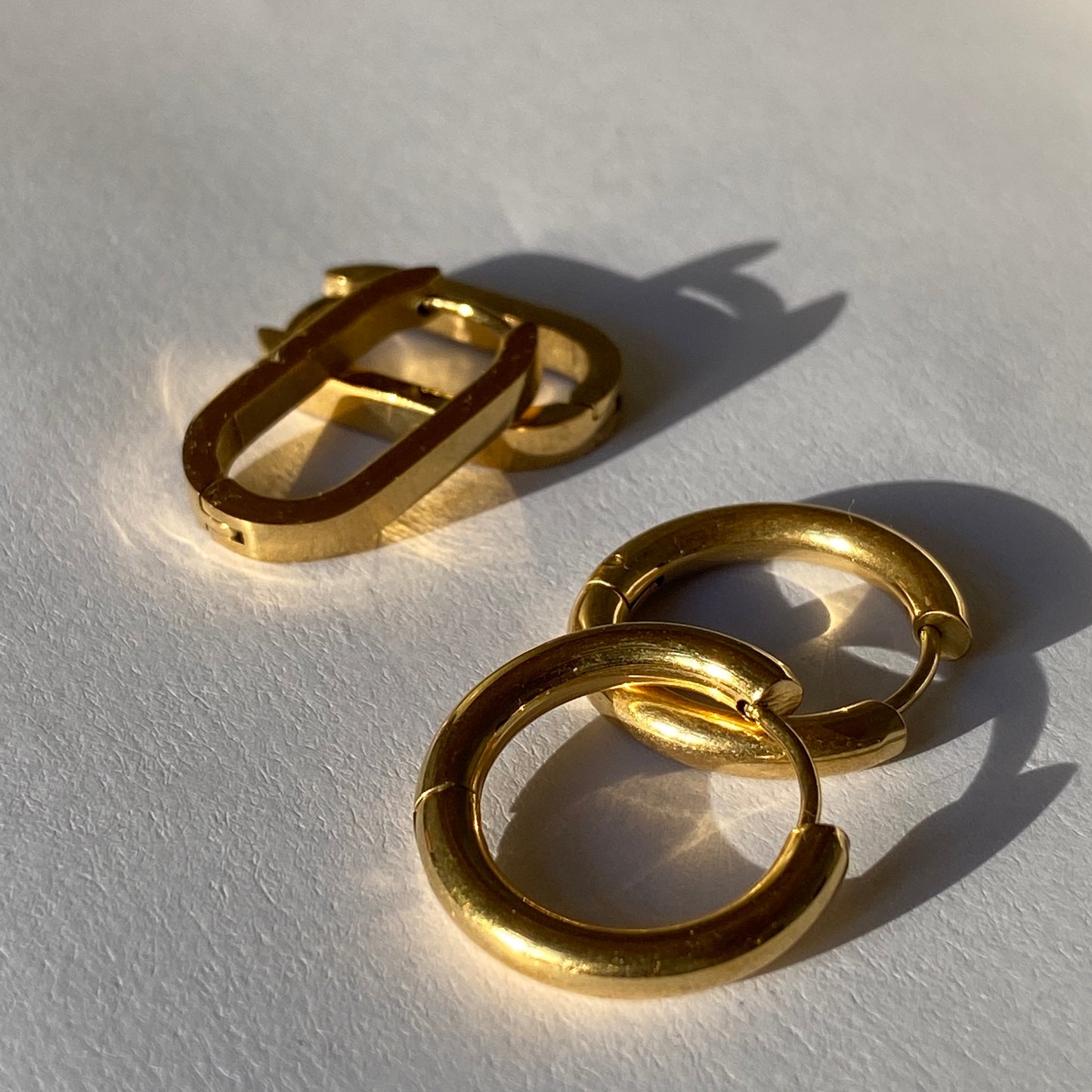 Oval Hoops Creolen Oval in gold auf weißer Steinplatte