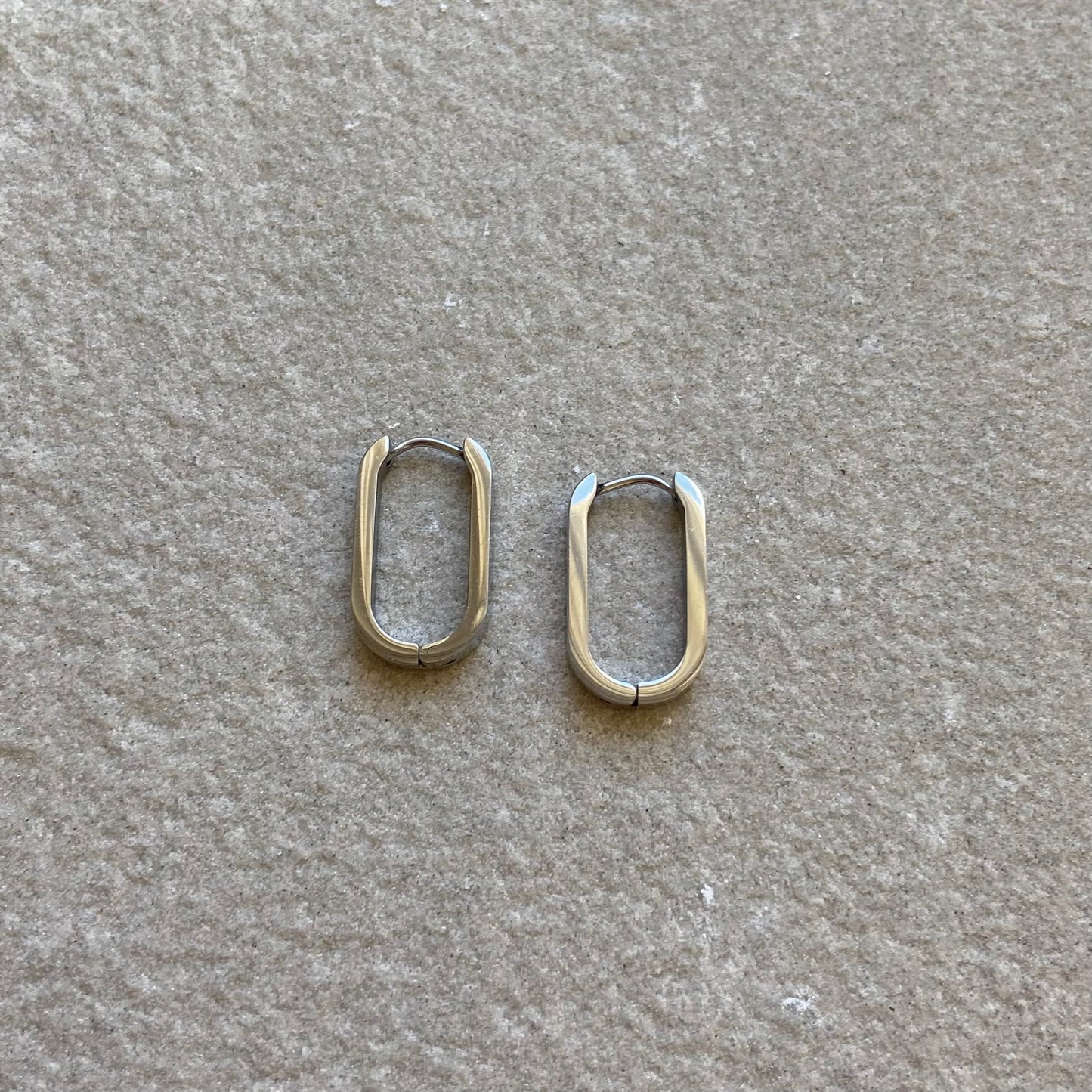 Oval Hoops Creolen Oval in silber auf grauer Steinplatte