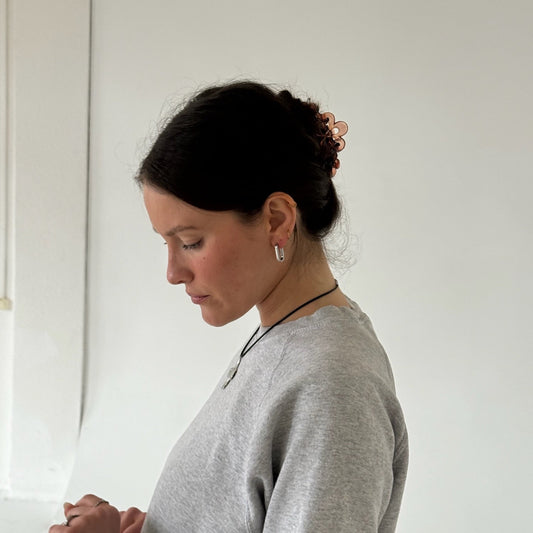 ovale Kreolen in Silber, getragen von Mädchen vor weißer Wand