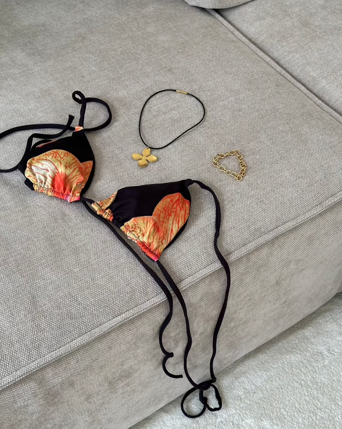 bikini laying om sofa with flower necklace and golden bracelet picture taken from above