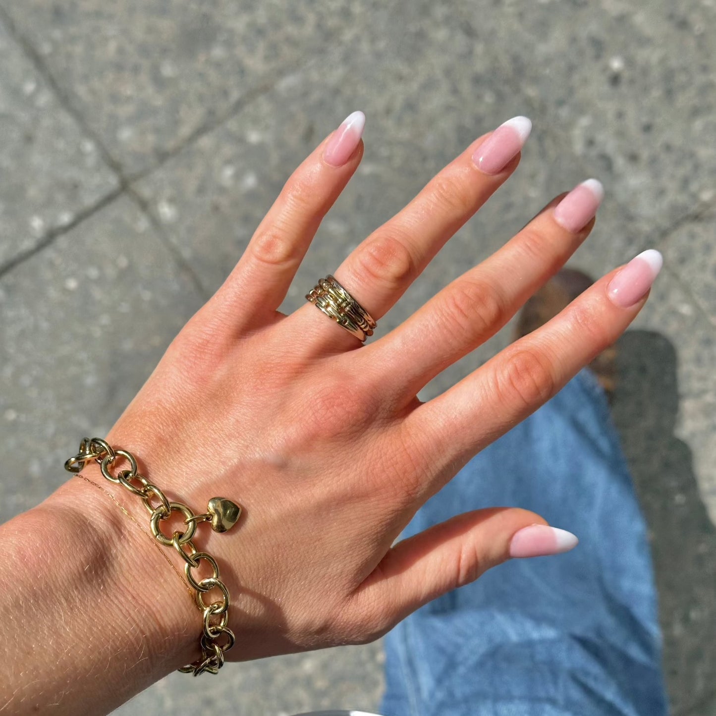 woman walking on the streets showing her ring stack on her hand and the oval bracelet with heart charm