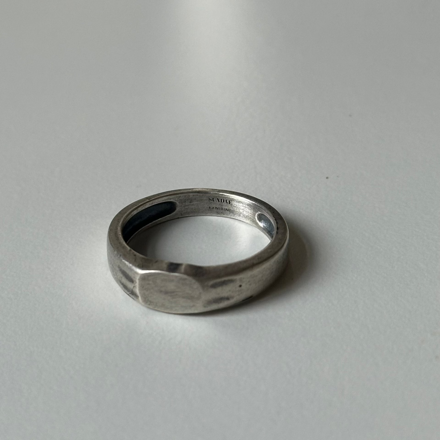 silver narrow signet ting on white table