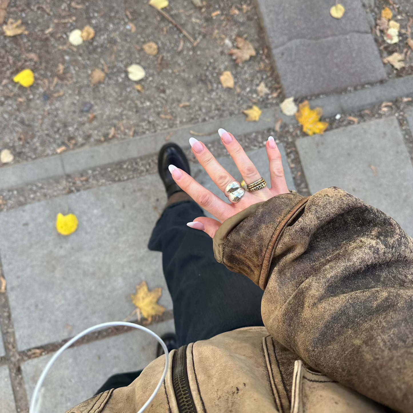 bold jewelry ring and gold ring stack worn on hand while walking the streets with yellow leafs on the ground