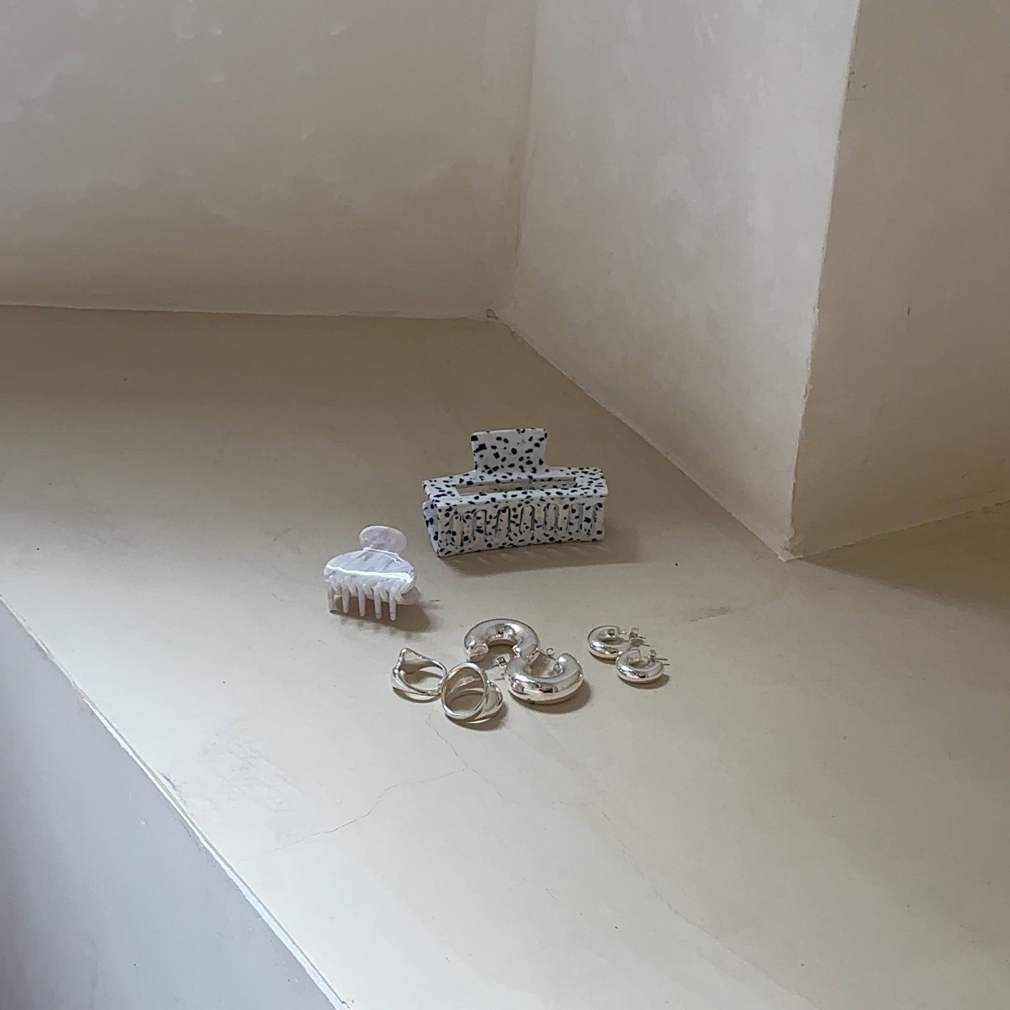 bold silver jewelry and hair clips in white on beige corner of the room