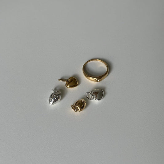 Gigi Ring und Herz und Erdbeeranhänger in Silber und Gold auf weißem Tisch