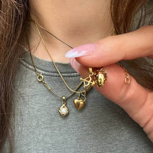 Drei Halsketten getragen auf Mädchen mit grünem T-Shirt, Nahaufnahme, Bogen und Pfeil Charm, Erdbeere Halskette, Herz aus Gold Halskette ani Birne Charm Halskette
