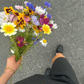 woman walking on streets with wildflower bouquets wearing golden bracelet