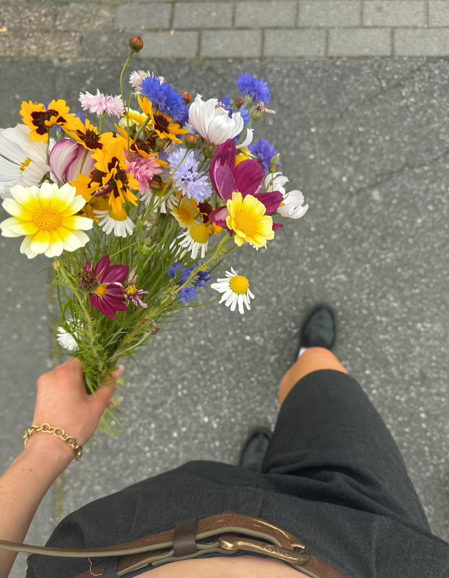 woman walking on streets with wildflower bouquets wearing golden bracelet
