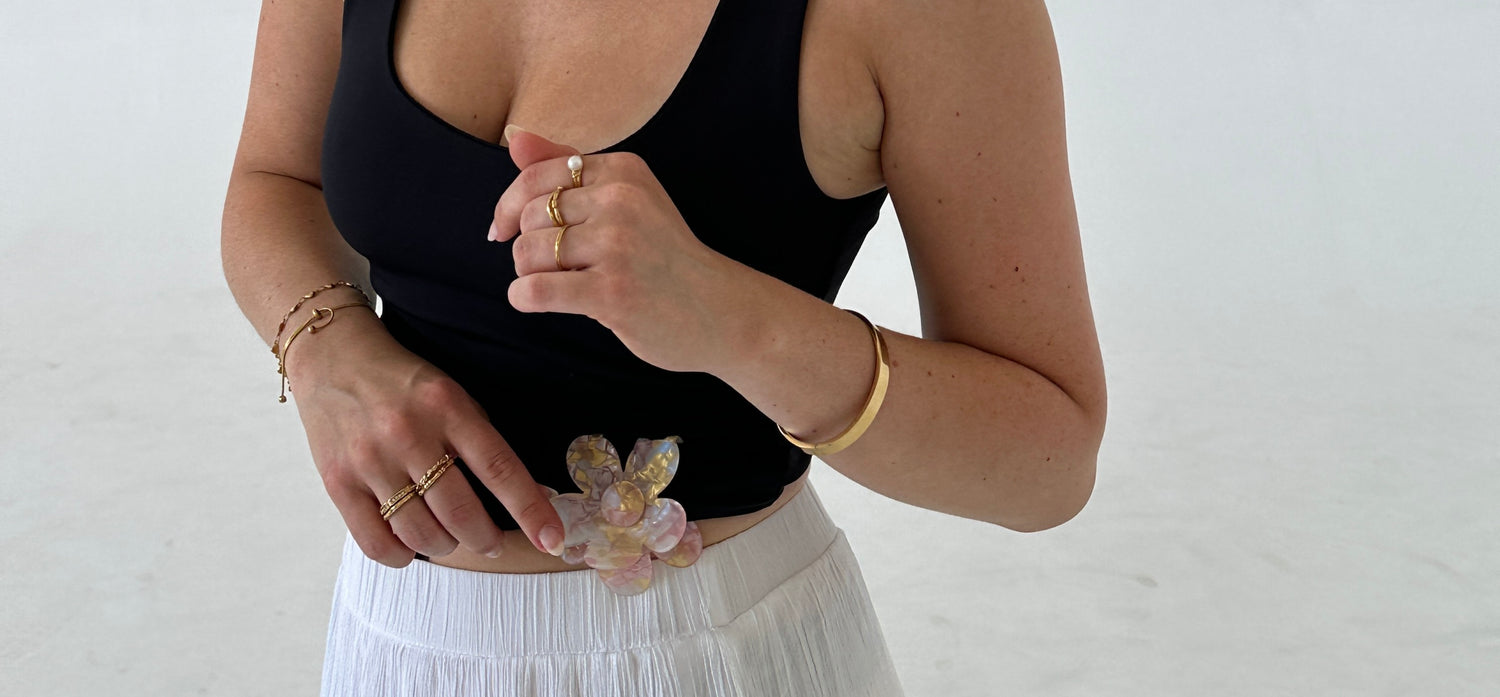 Goldene Armbänder an Handgelenk von Frau im sommerlichen Outfit