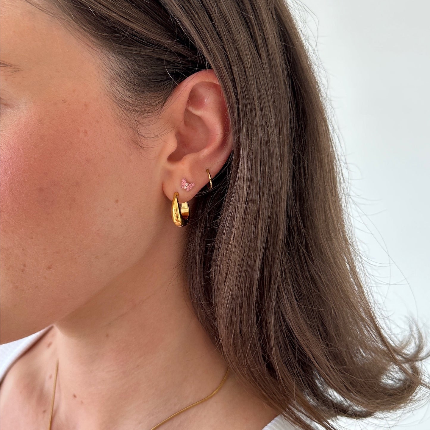 Hailey Hoops Tropfen Ohrringe in gold getragen an Frau mit anderen Ohrringen