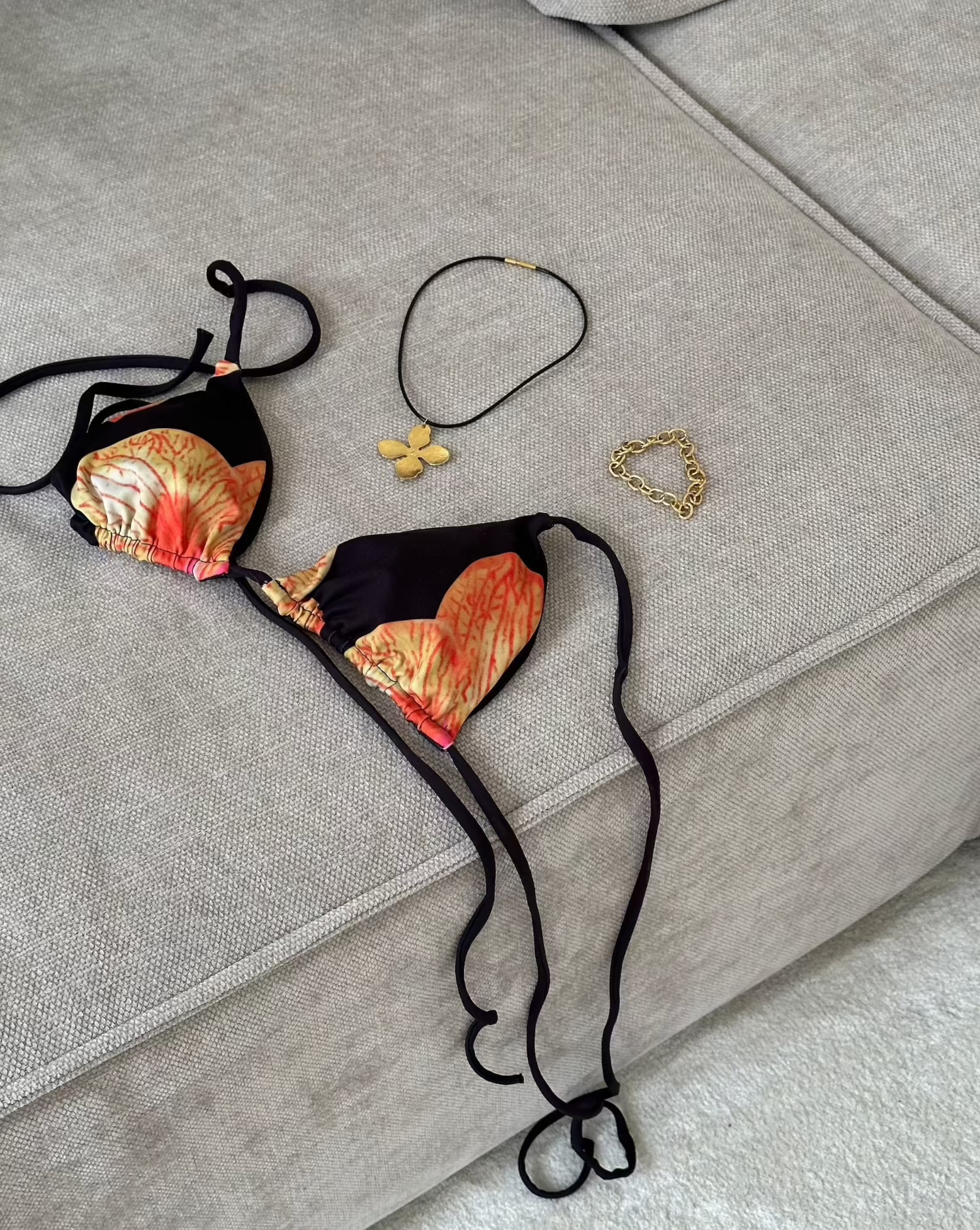 bikini laying om sofa with flower necklace and golden bracelet picture taken from above 